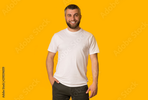 Positive bearded man posing over yellow background