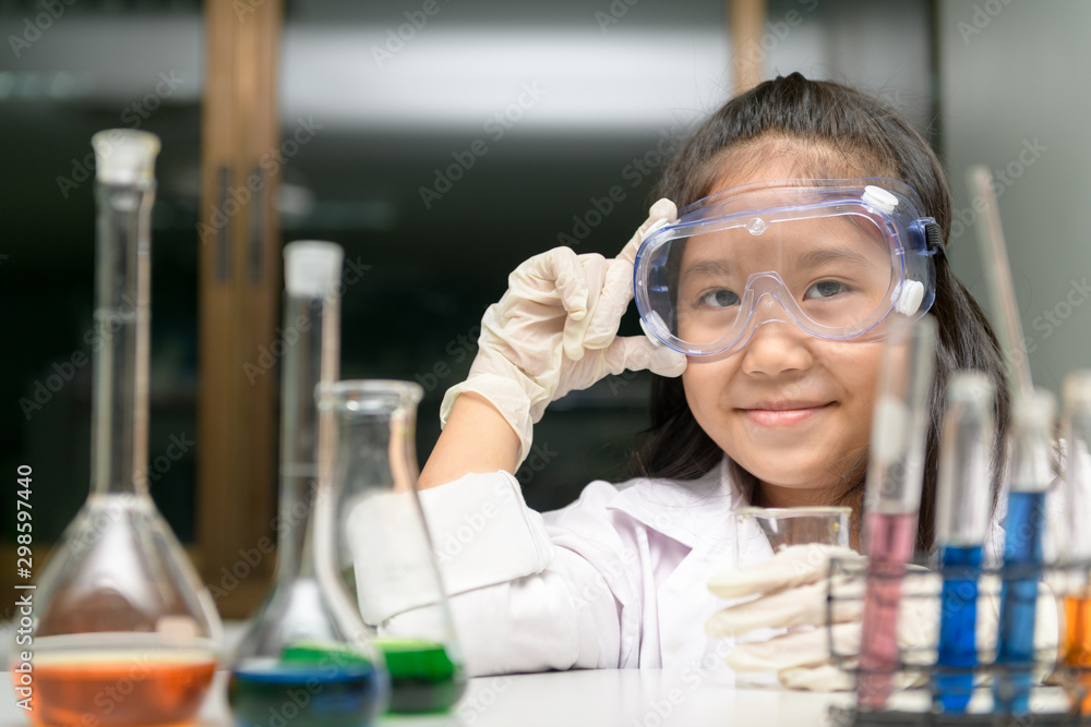 Cute little girl wearing safty goggle and lab coat making experiment Cute little girl wearing safty goggle and lab coat making experiment