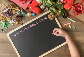 Kid writing New year resolution on black board