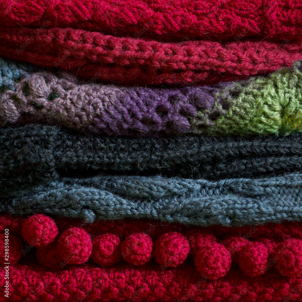 Bunch of knitted warm bright sweaters with different knitting patterns folded in stack, clearly visible texture. Stylish fall winter seasonal knitwear clothing. Closeup, copy space Bunch of knitted warm bright sweaters with different knitting patterns folded in stack, clearly visible texture. Stylish fall winter seasonal knitwear clothing. Closeup, copy space