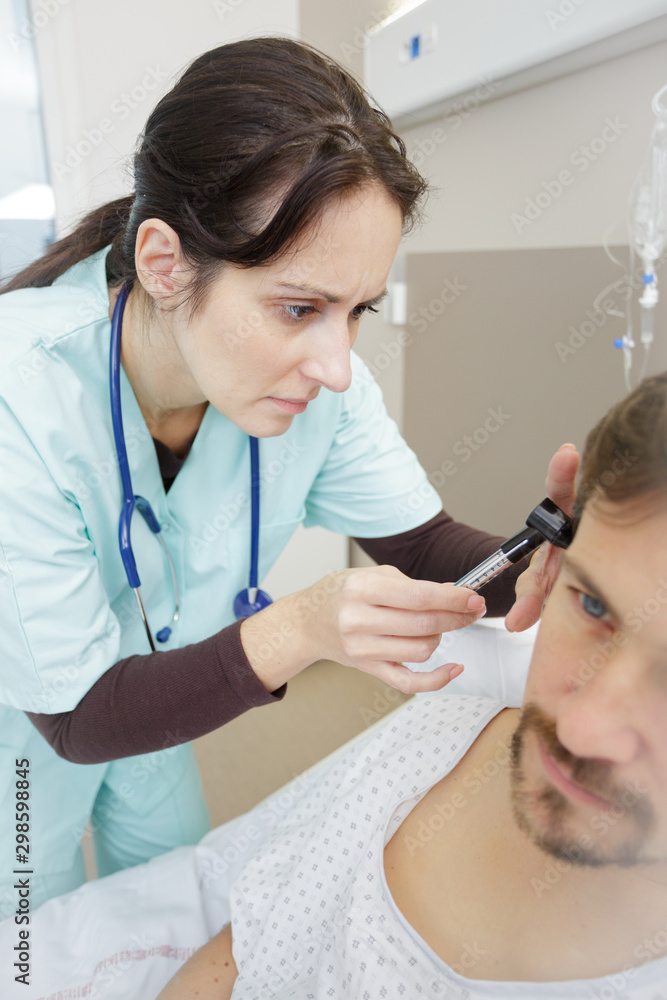 Fototapeta premium doctor inserting hearing aid in mans ear