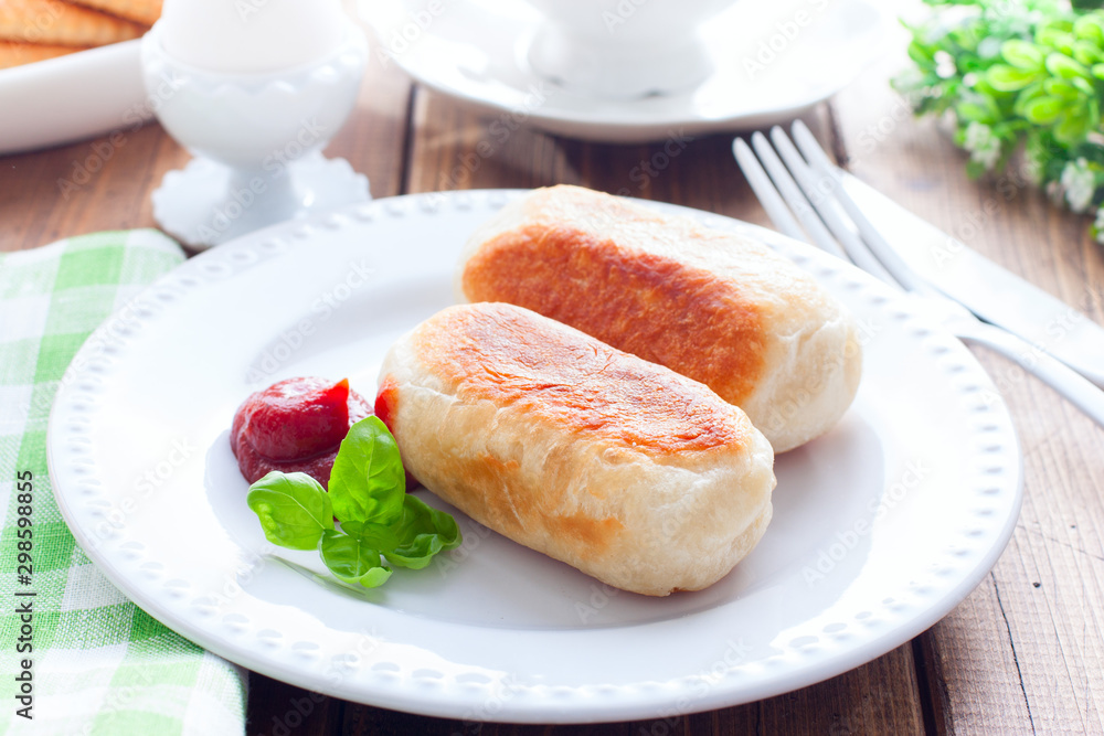 Breakfast with sausages in yeast dough on a wooden table, horizontal Breakfast with sausages in yeast dough on a wooden table, horizontal
