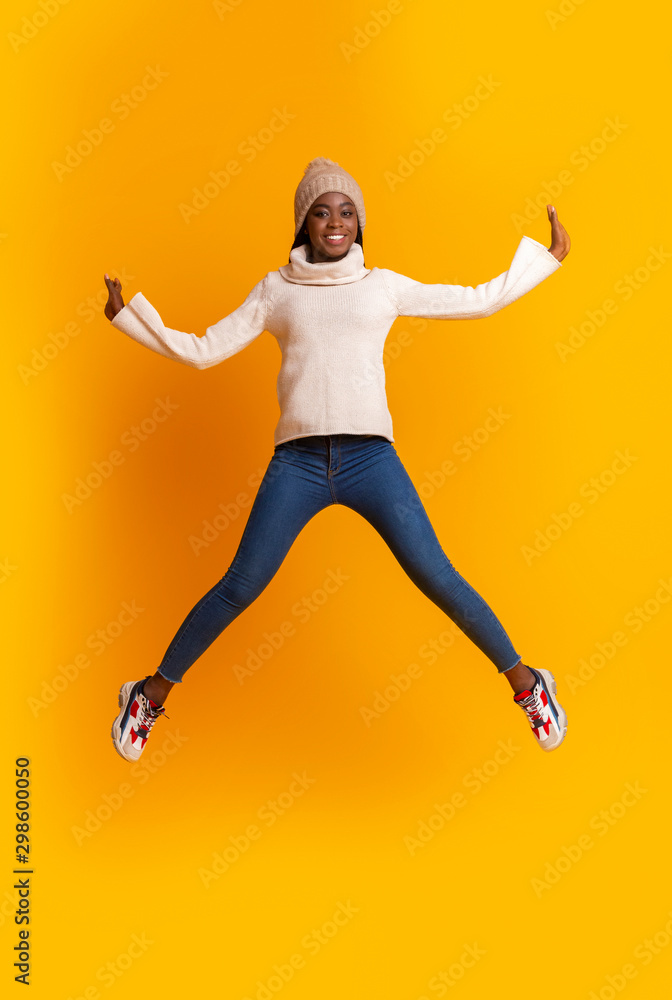 Emotional afro girl in winter hat jumping up