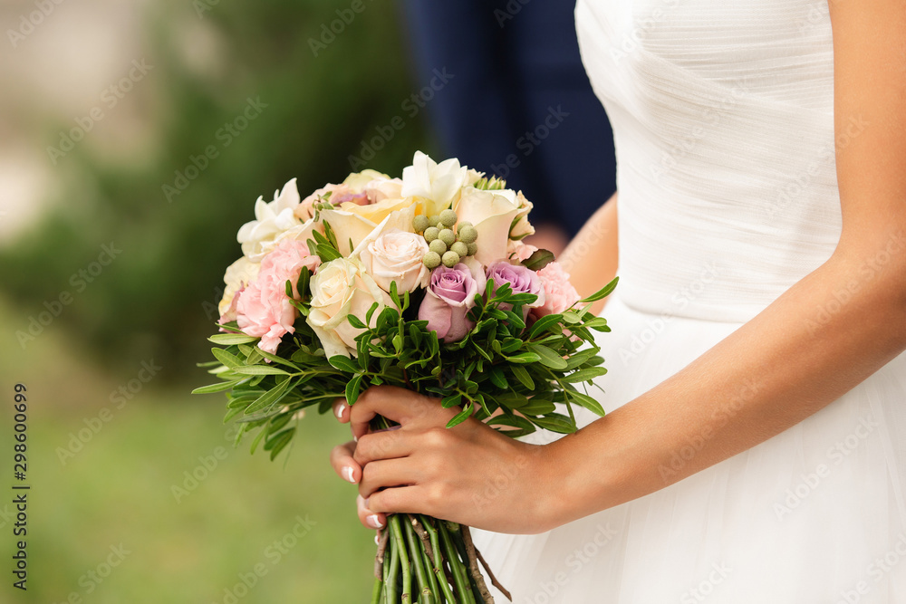 Bride in beautiful white wedding dress holding bouquet of fresh flowers at her happy wedding day Bride in beautiful white wedding dress holding bouquet of fresh flowers at her happy wedding day