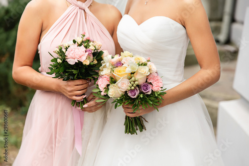 Wedding, marriage concept. Bride and bridesmaid in pink dress holding wedding bouquets