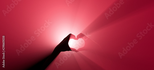 Symbol of love with a hand gesture. Red spotlight in the background.