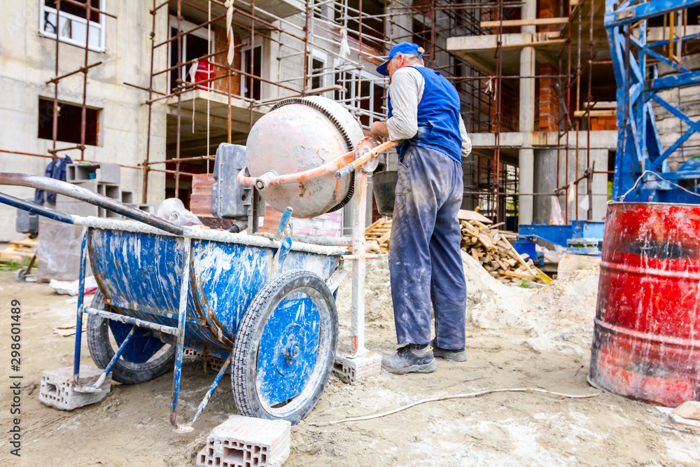 Worker is pour mortar in wheelbarrow Worker is pour mortar in wheelbarrow