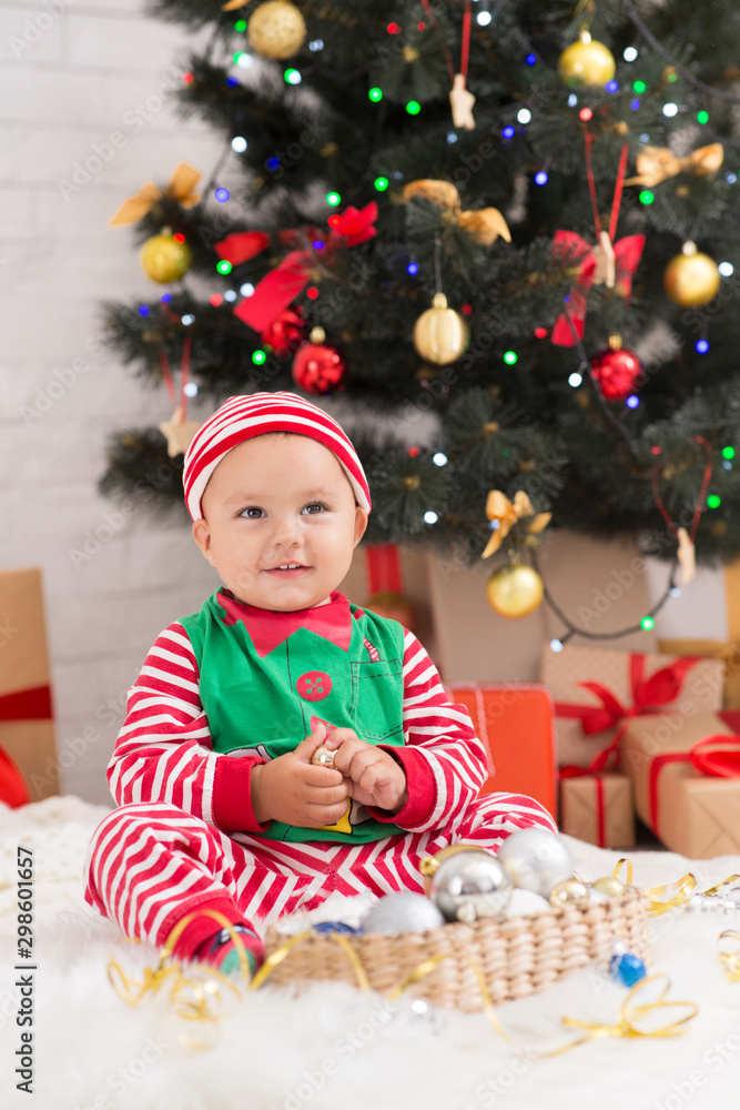 Adorable baby playing with decorations under Xmas tree Adorable baby playing with decorations under Xmas tree