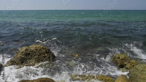 Close up shot of a blue waves of a beautiful sea crushing onto stones of a sea shore. photo