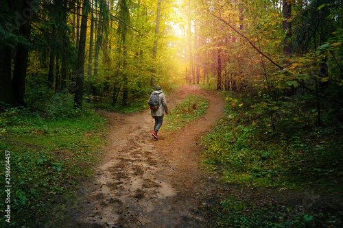 A man with backpack walks in the amazing autumn forest. Hiking alone along autumn forest paths. Travel concept. © v_sot