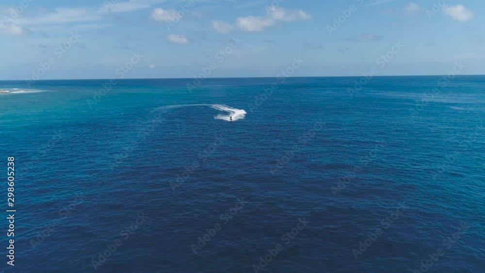 Drone tracking Slow motion shot Over Man Riding Jet Ski At Tropical Paradise Exotic Island with blue and turquoise ocean sea view. Adventure Concept for Tourist Attraction at Beach Vacation at Summer Drone tracking Slow motion shot Over Man Riding Jet Ski At Tropical Paradise Exotic Island with blue and turquoise ocean sea view. Adventure Concept for Tourist Attraction at Beach Vacation at Summer