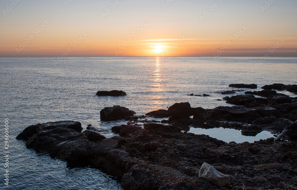 Sunrise near Cala Bona Mallorca with the suns rays reflecting off the water.