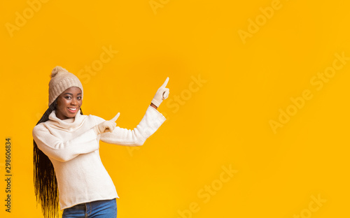 Emotional girl in winter hat pointing at empty space