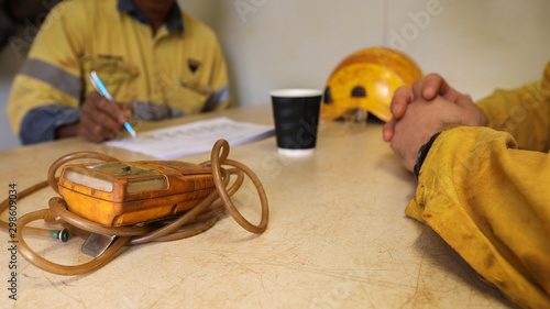 Defocused of senior miner supervisor hand written Job Hazard Analysis (JHS) risk assessment on the table with confined restricted space with gas tester atmosphere on the foreground  