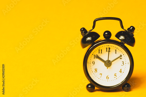 Classic alarm clock on yellow background. vintage watch with round dial