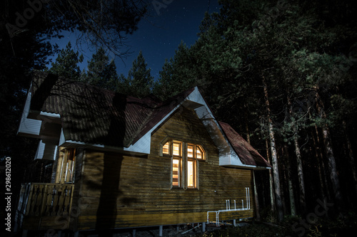 Old spooky house at the pine forest at night. Horror Halloween concept