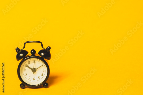 Classic alarm clock on yellow background. vintage watch with round dial