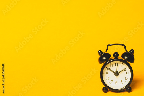 Classic alarm clock on yellow background. vintage watch with round dial photo