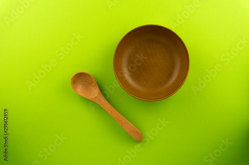 Wooden spoon, and bowl isolated on Green background.