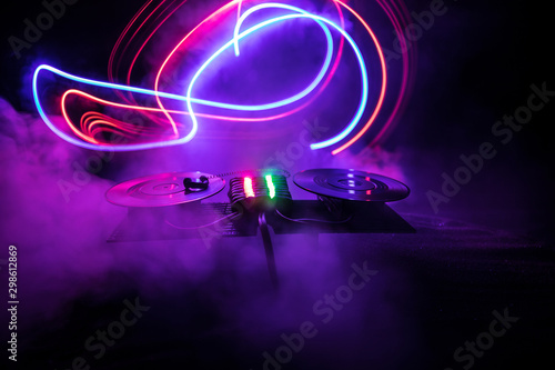 Dj club concept. Creative artwork decoration of dj table on dark toned background with lights and fog.