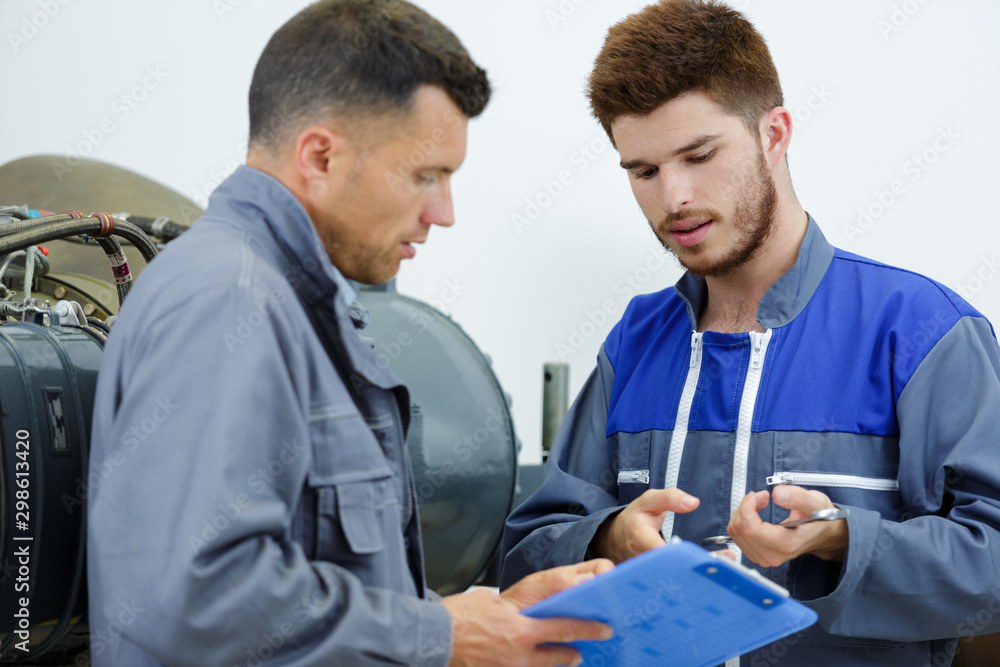 Obraz premium two automobile mechanics checking checklist