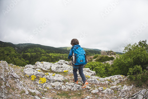 The boy walks along a mountain path.