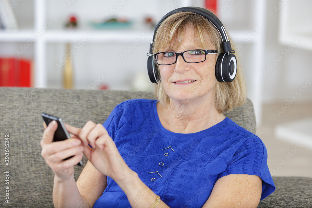 mature woman with headphones listening to music on a phone