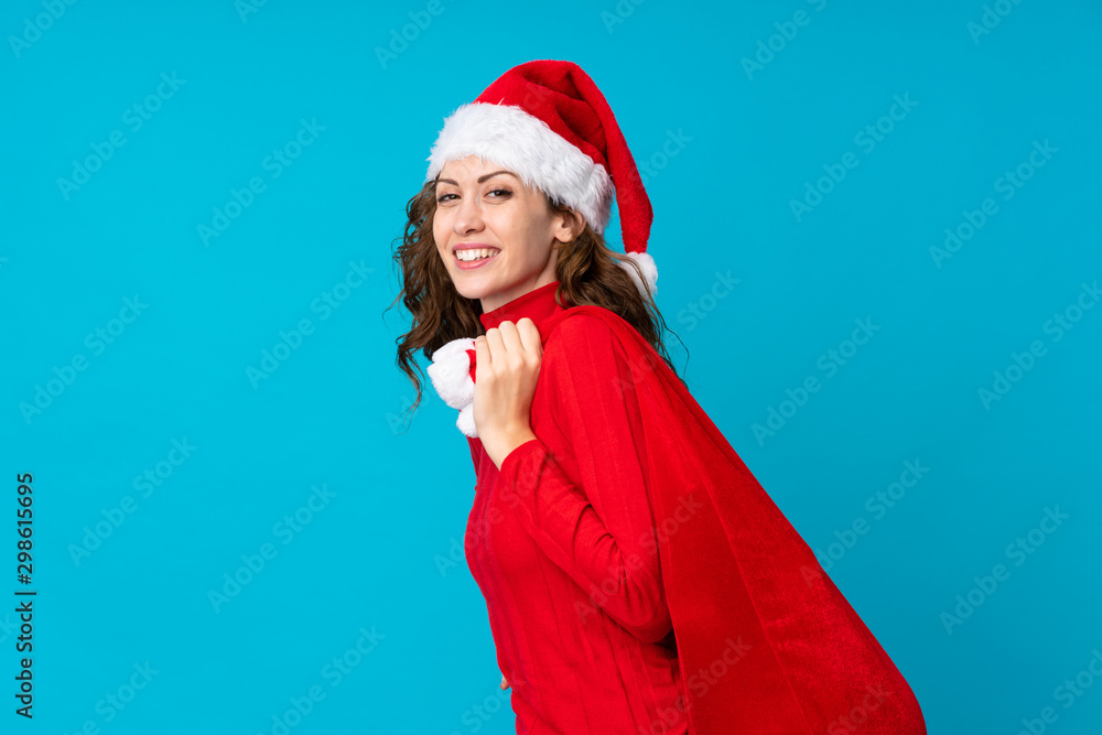 Girl with christmas hat holding a christmas bag full of gifts over isolated background Girl with christmas hat holding a christmas bag full of gifts over isolated background