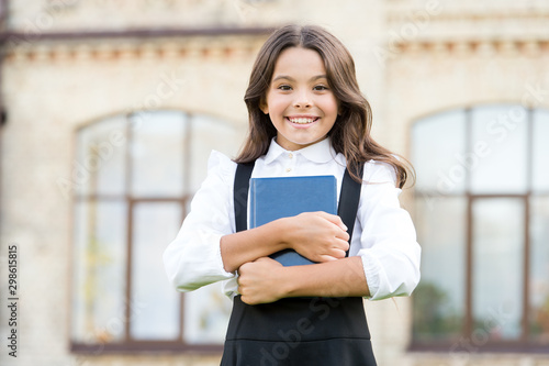 Little expert in books. Happy girl hold library book outdoor. School bibliopole. Bibliopole and bibliomania. Bibliopole and librarian. Bibliopole or book dealer. Small bookworm. Second-hand bookstore photo