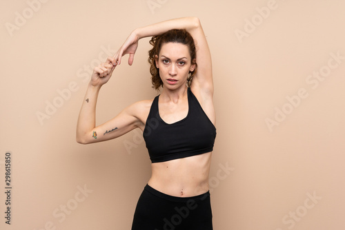 Young sport woman over isolated background stretching © luismolinero