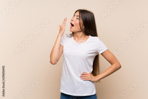 Pretty young girl over isolated background yawning and covering wide open mouth with hand