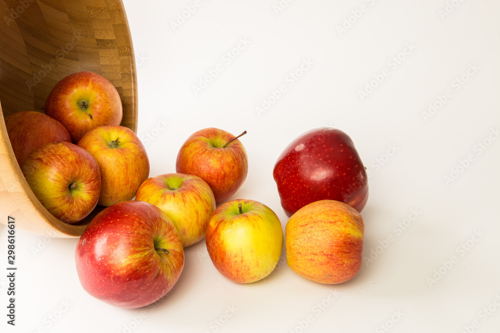 Red apples are falling from the brown Plate on the white background Red apples are falling from the brown Plate on the white background