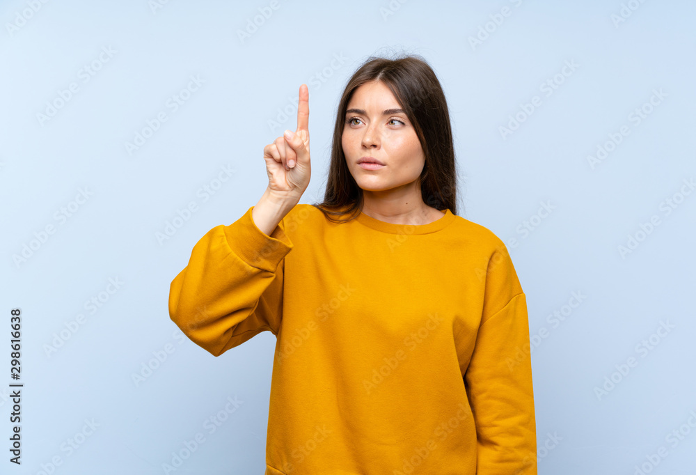 Caucasian young woman over isolated blue wall touching on transparent screen Caucasian young woman over isolated blue wall touching on transparent screen