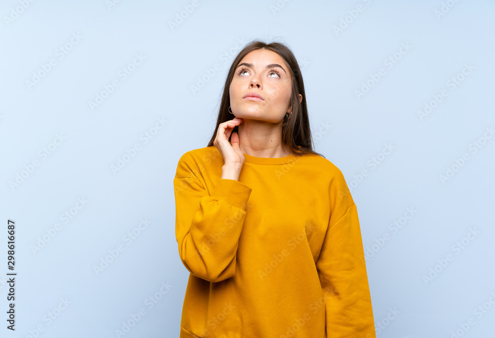 Caucasian young woman over isolated blue wall thinking an idea Caucasian young woman over isolated blue wall thinking an idea