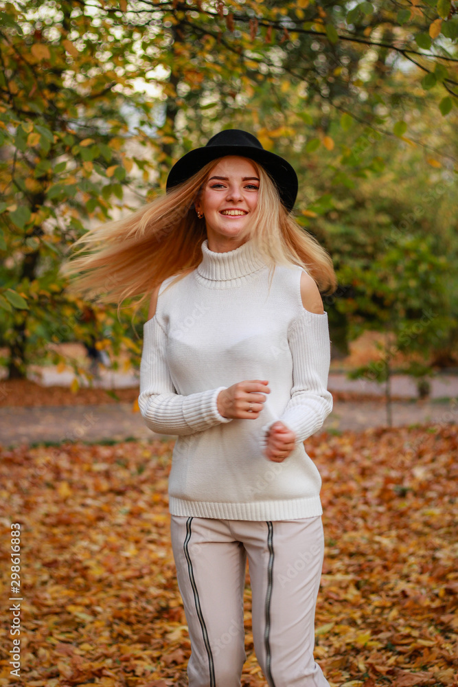 Autumn girl portraits. Model in a white sweater is spinning. Black hat. Yellow leaves. Atmospheric photos. Autumn girl portraits. Model in a white sweater is spinning. Black hat. Yellow leaves. Atmospheric photos.
