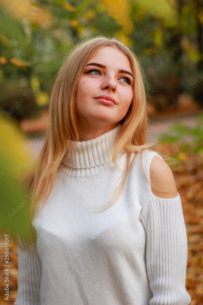 Fototapeta premium Autumn girl portraits. Model in white sweater Yellow leaves. Atmospheric photos.