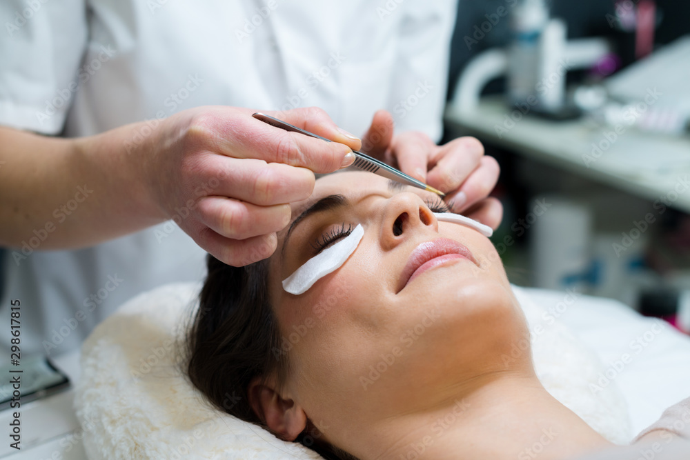 close up of beautician tweezing patients eyebrows close up of beautician tweezing patients eyebrows