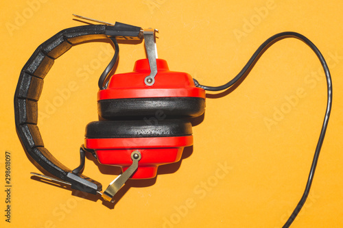 Vintage red headphones on yellow background. classic earphones