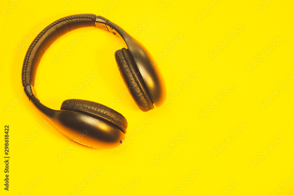 Black wireless headphones on a yellow background Black wireless headphones on a yellow background