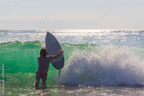 Male surfer entering the sea with his board.Ready for a great surfing day.