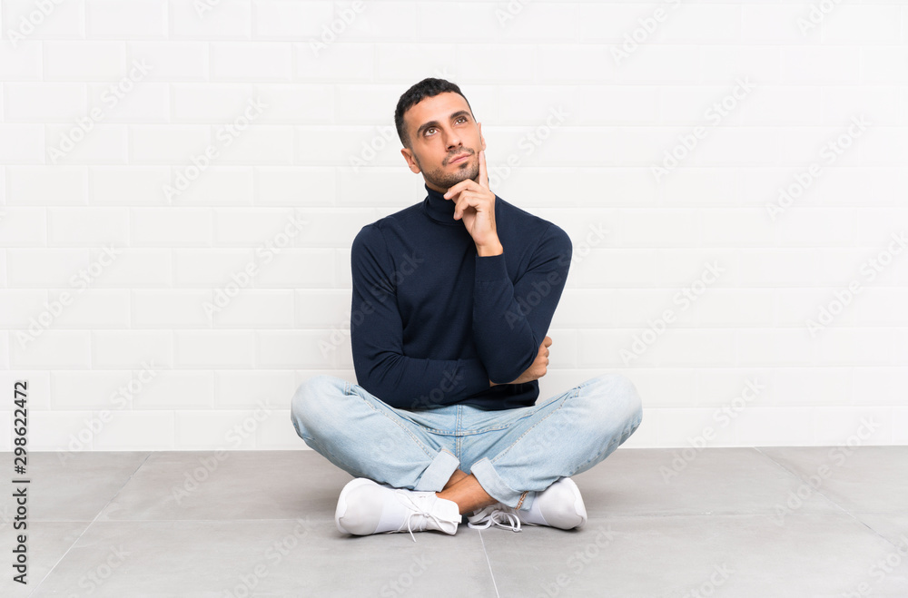Young handsome man sitting on the floor thinking an idea Young handsome man sitting on the floor thinking an idea
