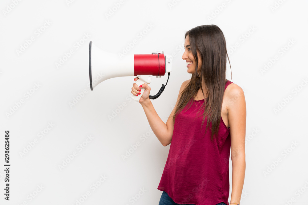 Young woman over isolated white background shouting through a megaphone