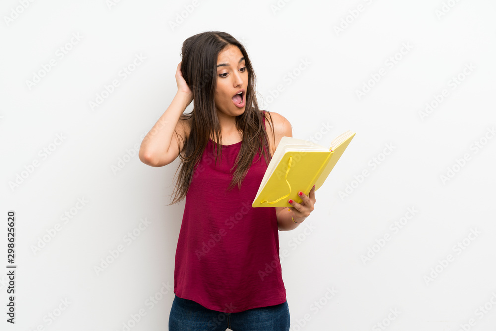 Young woman over isolated white background holding and reading a book Young woman over isolated white background holding and reading a book