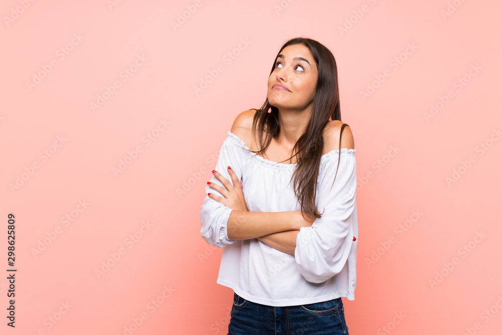 Young woman over isolated pink background making doubts gesture while lifting the shoulders Young woman over isolated pink background making doubts gesture while lifting the shoulders