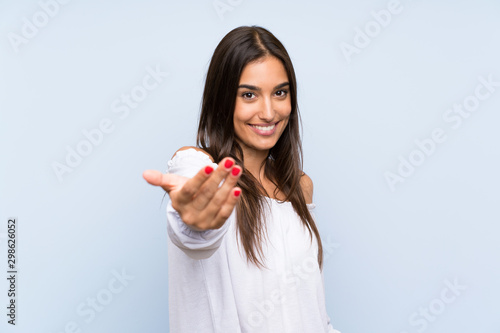 Young woman over isolated blue background inviting to come photo