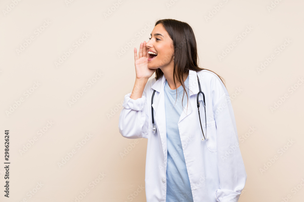 Young doctor woman over isolated background shouting with mouth wide open Young doctor woman over isolated background shouting with mouth wide open
