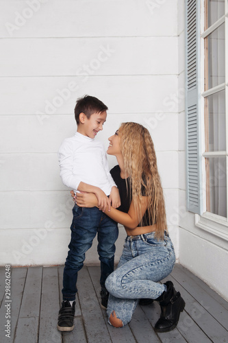 Beautiful excited asian woman mother having fun and playing with her little son on the white porch of a country vacation house. Mixed race Asian and Caucasian family portrait on their front porch © Алина Троева