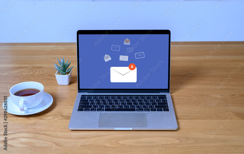 Fototapeta premium Laptop computer on wooden table with email communication connection message online and chat on social media with global letters concept. Laptop mockup with clipping path on screen.