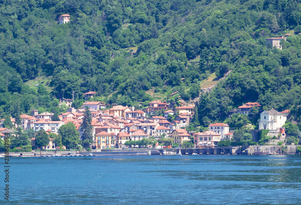 town surrounded by nature with the mountains behind it and a marina on Lake Maggiore. Piedmont - Italy