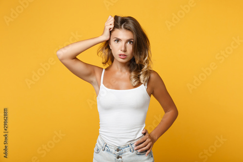 Perplexed young woman girl in light casual clothes posing isolated on yellow orange background, studio portrait . People sincere emotions lifestyle concept. Mock up copy space. Putting hand on head.